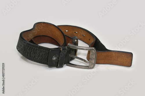 Used and Old black leather belt with buckle isolated on white background. photo