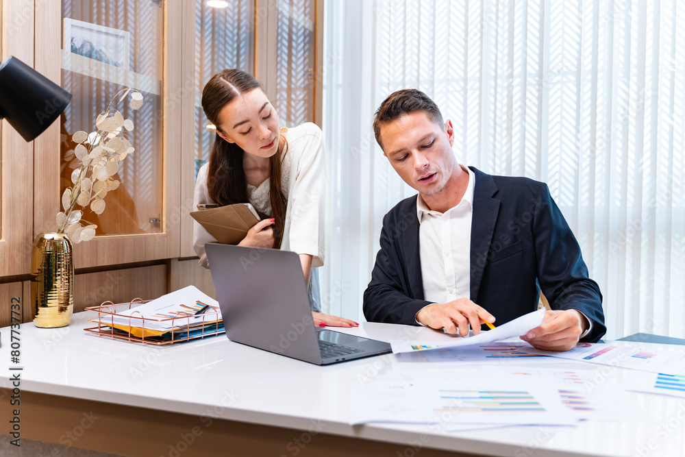 Caucasian businessman and secretary are looking at the increasing of sales report from marketing team with joy for business team management Caucasian businessman and secretary are looking at the increasing of sales report from marketing team with joy for business team management