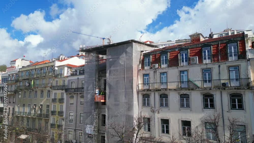 Aerial view from Lisbon city with a building under construction with workers descending on an elevator platform,Lisbon,Portugal. Backwards drone shot. Aerial view from Lisbon city with a building under construction with workers descending on an elevator platform,Lisbon,Portugal. Backwards drone shot.