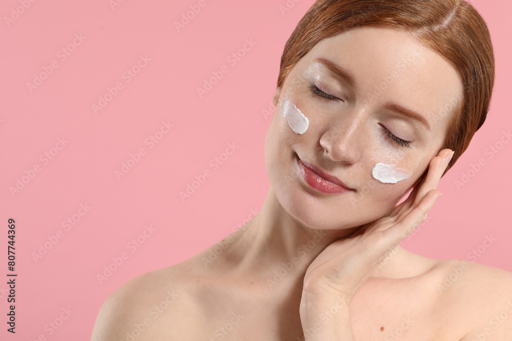Beautiful woman with freckles and cream on her face against pink background. Space for text Beautiful woman with freckles and cream on her face against pink background. Space for text
