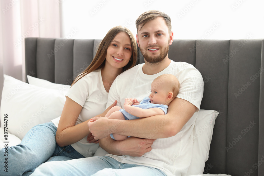 Happy family. Parents with their cute baby on bed indoors Happy family. Parents with their cute baby on bed indoors