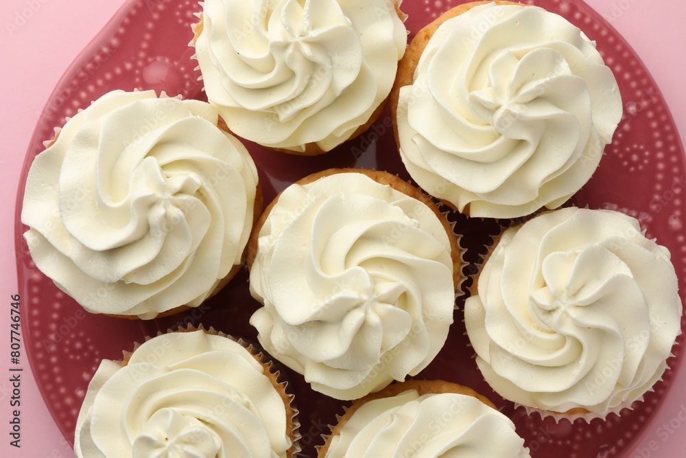 Tasty vanilla cupcakes with cream on pink background, top view Tasty vanilla cupcakes with cream on pink background, top view