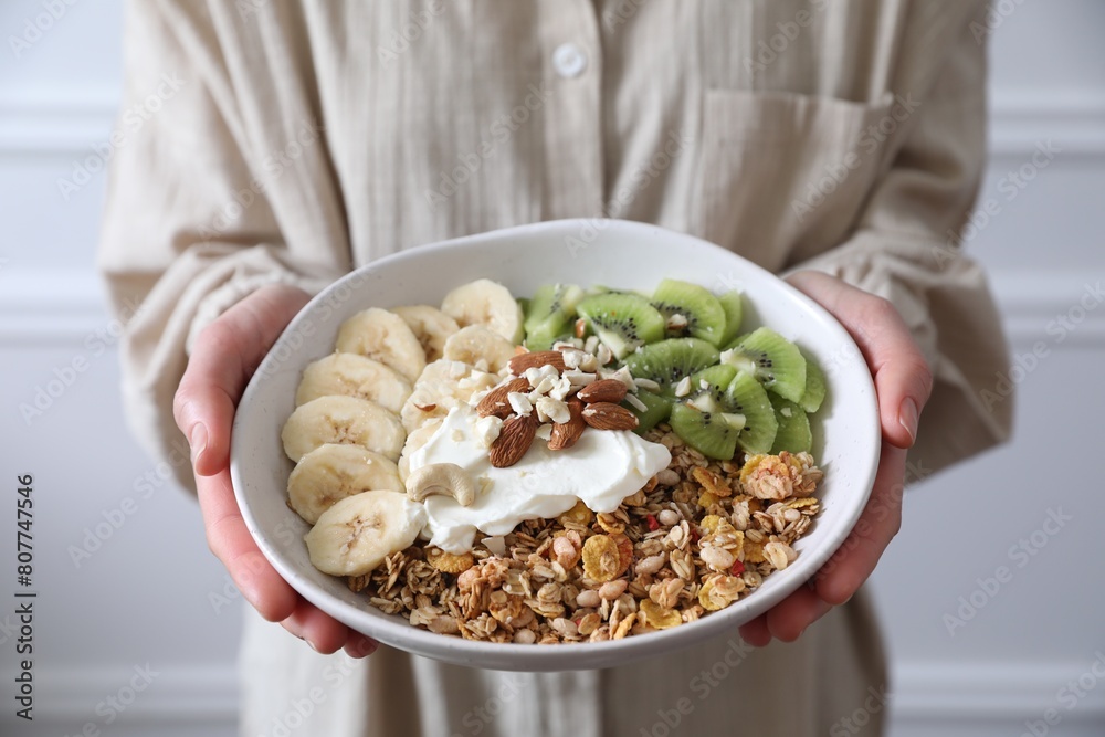 Woman holding bowl of tasty granola indoors, closeup Woman holding bowl of tasty granola indoors, closeup