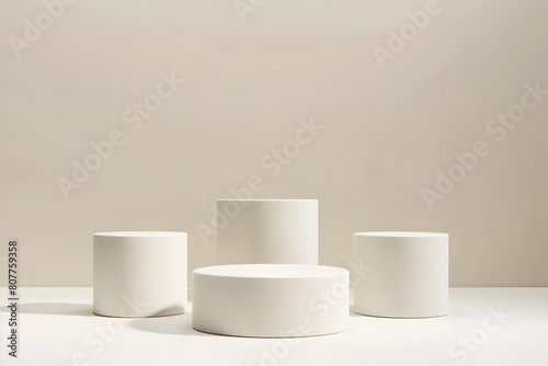 Three Minimalist White Cylindrical Podiums of Varying Heights on an Off White Background