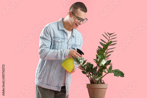 Young man watering plant wi...