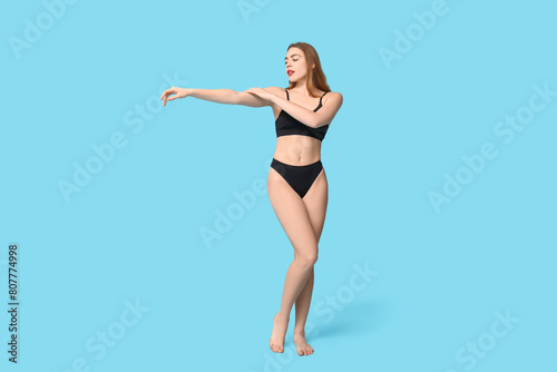 Pretty young woman in black cotton underwear on blue background