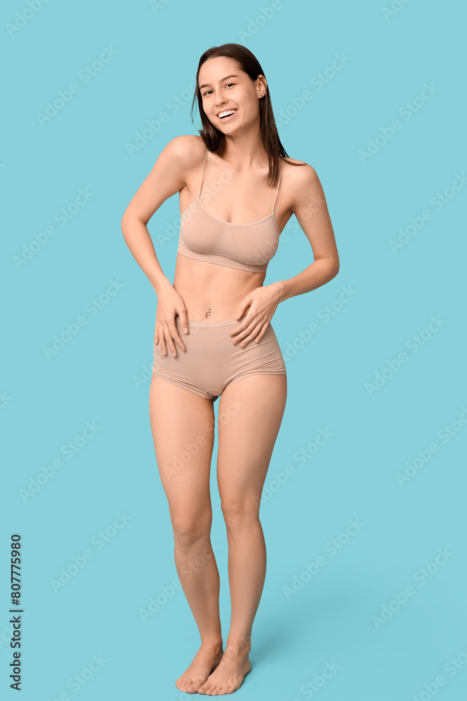 Beautiful young woman in nude underwear on blue background Beautiful young woman in nude underwear on blue background
