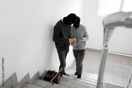 Male thieves counting stolen money in stairway photo
