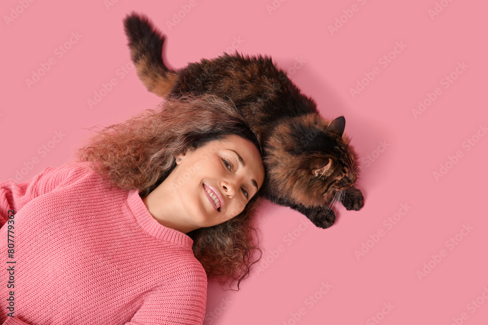 Mature woman with cute cat lying on pink background Mature woman with cute cat lying on pink background