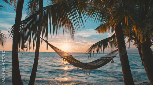 A hammock hangs between palm trees on a tropical island against the background of the sea