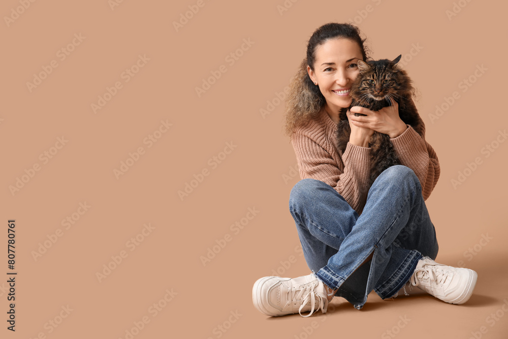 Beautiful mature woman with cute cat sitting on brown background Beautiful mature woman with cute cat sitting on brown background