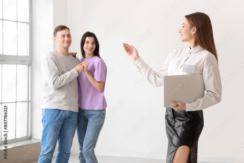 Fototapeta premium Female realtor with laptop showing young couple new house