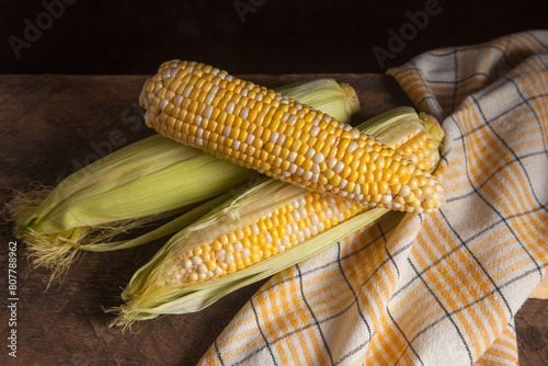 Several cobs sweet corn on wooden background..