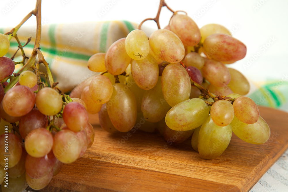 Close up view of bunch of organic pink grapes on wooden cutting board.. Close up view of bunch of organic pink grapes on wooden cutting board..