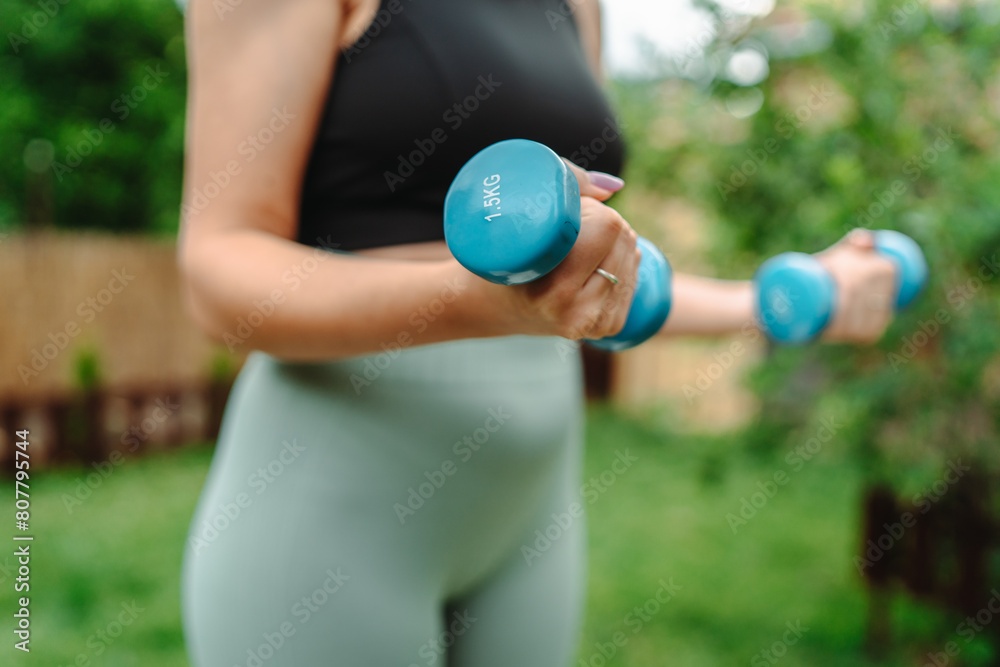 One young caucasian woman is doing exercises with dumbbells One young caucasian woman is doing exercises with dumbbells