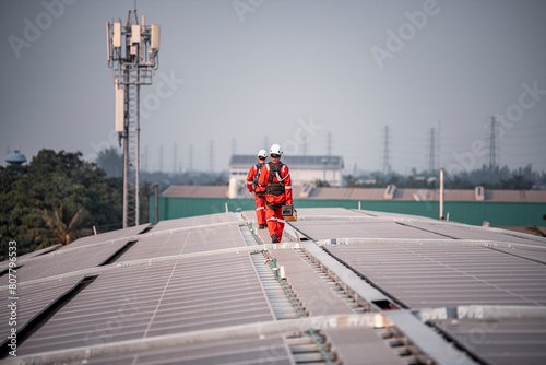 Engineers walking and holding box on factory roof inspection survey and check solar cell panel .Solar cell is smart grid sustainable ecology energy sunlight alternative power factory concept.