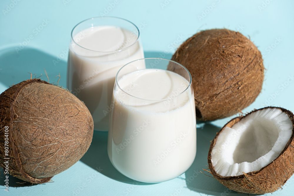 Coconut milk in a glasses among coconuts on a blue background Coconut milk in a glasses among coconuts on a blue background