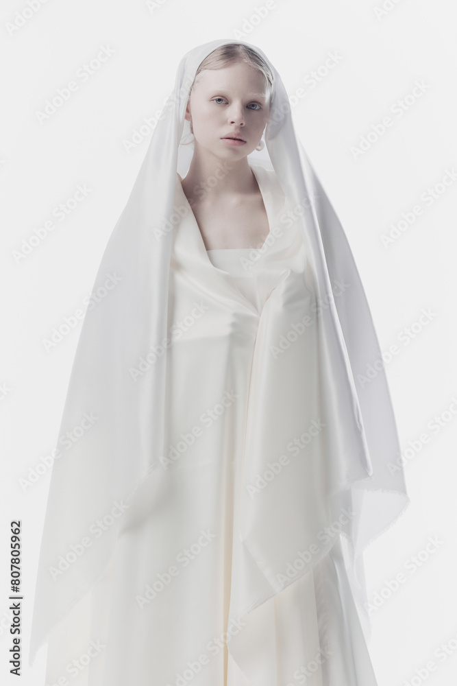 Portrait of young woman with pale skin and blonde hair looking calmly at camera, as maid or angel against white studio background. Concept of history, renaissance art, comparison of eras, vintage.