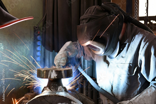 Welder in protective clothing at the workplace in an industrial company in steel construction