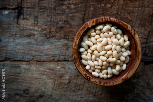 White beans in a wooden bowl. Wooden surface. Copy space