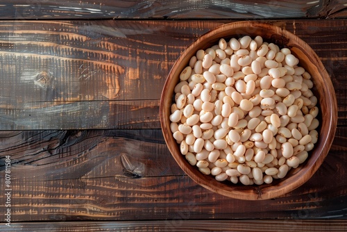 White beans in a wooden bowl. Wooden surface. Copy space