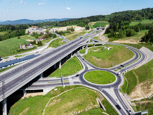 Poland. New Zakopianka multilane highway with a tunnel, multilevel spaghetti junction, crossroad with traffic circles, viaducts, entrance and exit ramps and traffic near Skomielna Biała. Aerial wiew