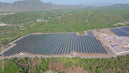 Wide aerial view of solar farm with rows of PV panels in middle of jungle photo