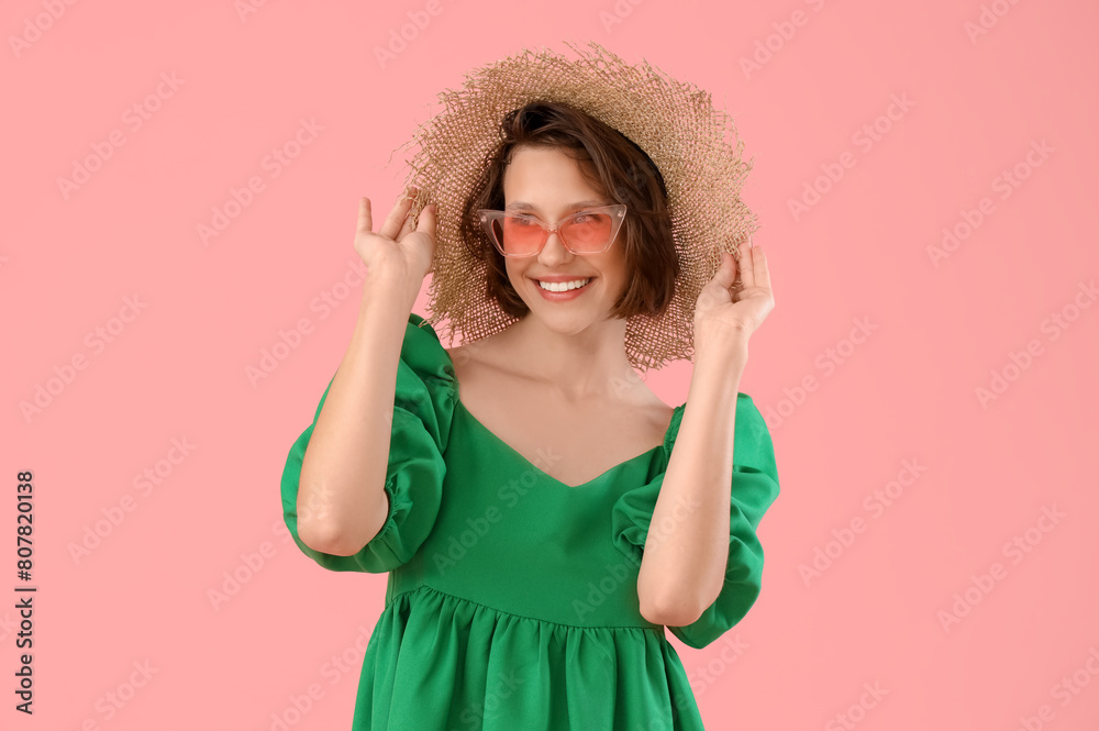 Pretty young woman with sunglasses and straw hat on pink background Pretty young woman with sunglasses and straw hat on pink background