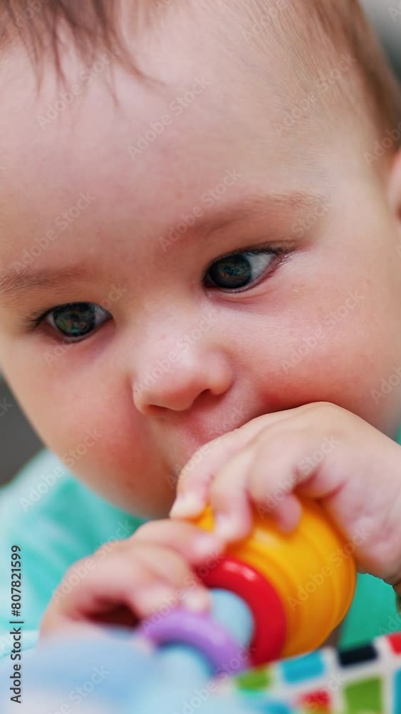 Darling little boy is busy playing with his toy. Child lies on belly waving with a toy. Close up. Blurred backdrop. Vertical video Darling little boy is busy playing with his toy. Child lies on belly waving with a toy. Close up. Blurred backdrop. Vertical video