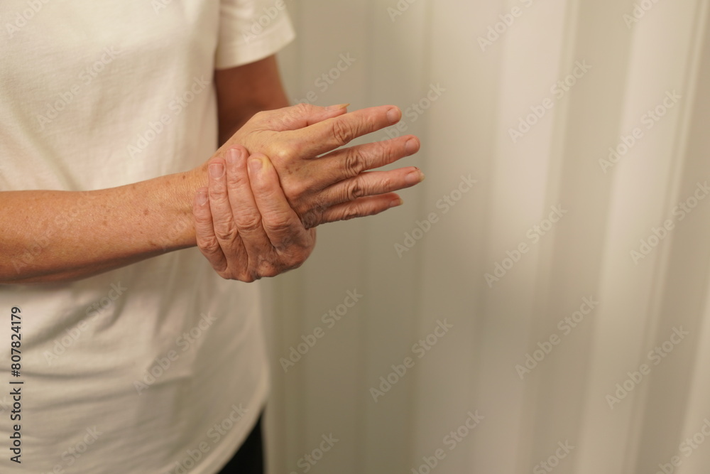 A woman uses her other hand to feel pain. and tingling along with symptoms of numbness in the hands Elderly woman tries to massage herself to relieve wrist pain