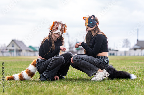 Teenage girls with cat mask and gloves doing Quadrobics. girls in a cat mask is lying on the grass.