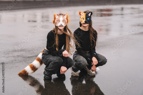 Teenage girls with cat mask and gloves doing Quadrobics. girls in a cat mask is lying on the grass.