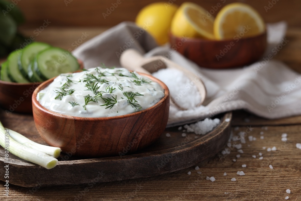 Delicious yogurt, green onion, dill and cucumbers on wooden table, closeup Delicious yogurt, green onion, dill and cucumbers on wooden table, closeup