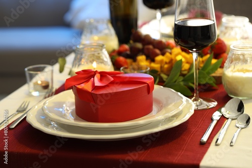 Stylish table setting with wine and gift box. Romantic dinner