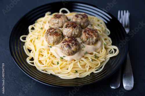 Swedish noisettes (fricandel) with spaghetti and Brune Sos creamy sauce. Traditional meatballs with garnish. Selective focus, close-up.