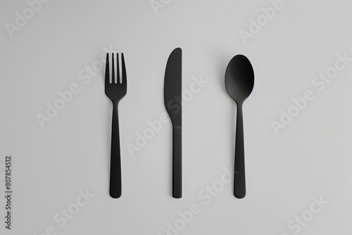 A knife  fork  and spoon gracefully arranged on a pristine white surface  creating a harmonious scene of culinary elegance.