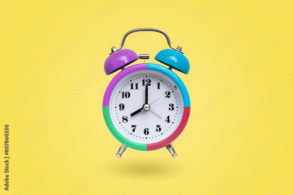 Colourful alarm clock isolated on yellow background Colourful alarm clock isolated on yellow background