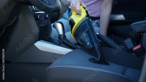 Female cleaning seats with vacuum in vehicle. A view of female cleaning fabric inside the car with portable modern cleaner inside. photo
