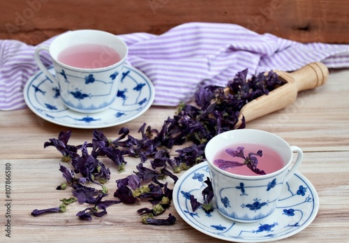 Two cups of herbal tea from dried flowers of Wild mallow, lat.  Malva sylvestris. Traditional curative herbal tea against cough.  Dried flowers in bowl and around.