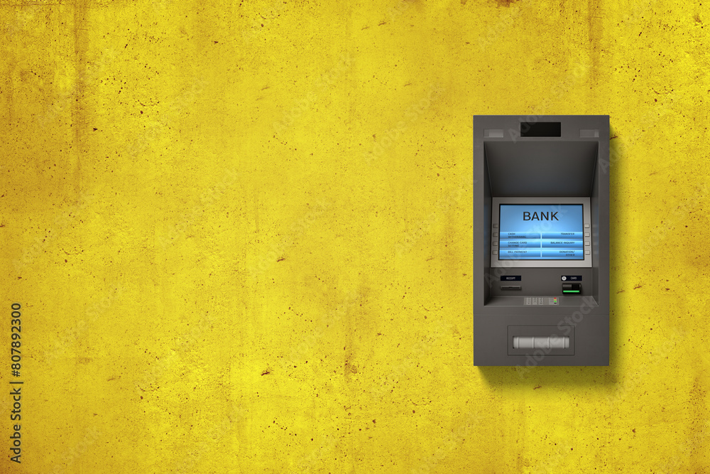 ATM machine on textured yellow wall background ATM machine on textured yellow wall background