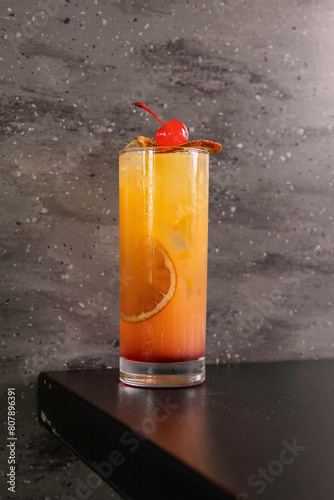 Cocktail alcolico all'arancia guarnito con fette di arancia affumicate e una ciliegia caramellata