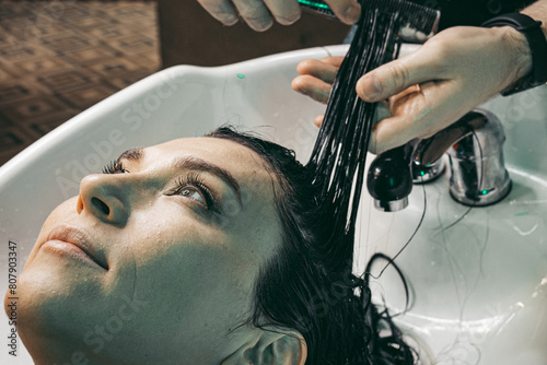 Hairdresser washing woman's hair. Man young hairdresser professional ,washing and combing hair head female client in hairdressing salon .close up shot 
