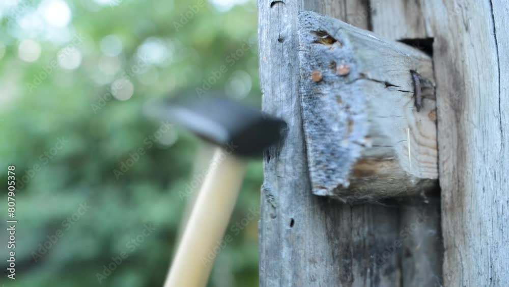 Man hammers hammering a nail into the wall of an old wooden barn. Man hammers hammering a nail into the wall of an old wooden barn.