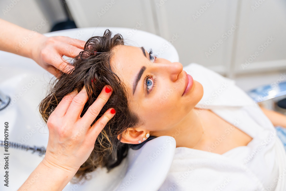 Naklejka premium Hairdresser washing the damaged hair of a beauty woman