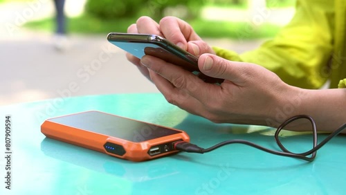 4k footage ogf Female hands using mobile phone while charging it with a portable power bank