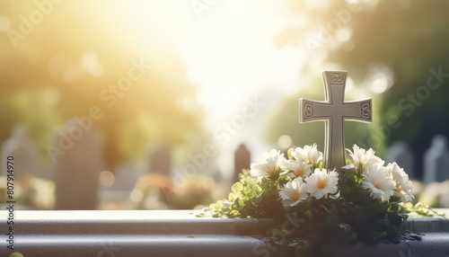 A cemetery with a cross and a casket with flowers on top