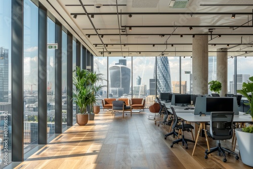 Spacious open-plan office with large windows offering a view of the city skyline, filled with natural light