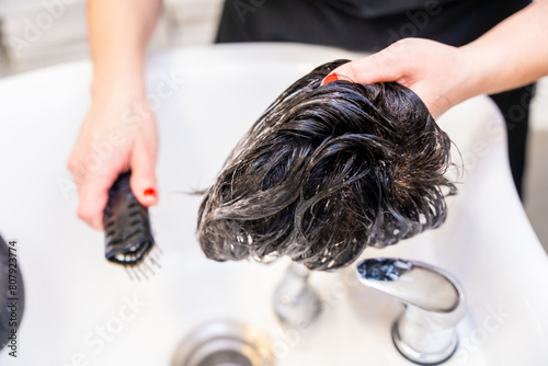 Hairdresser combing a wig after clean it in the salon