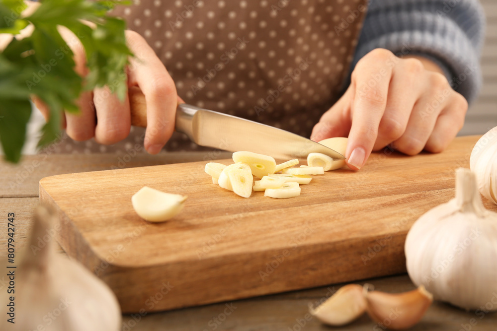 Woman cutting fresh garlic at table, closeup Woman cutting fresh garlic at table, closeup
