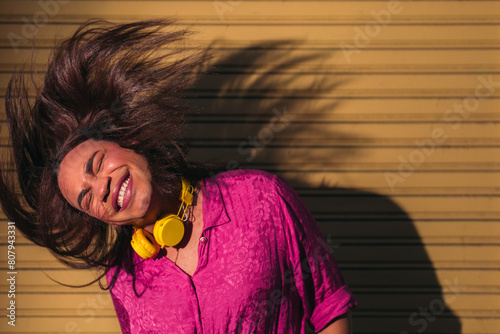 Funny portrait of trans woman shaking head against yellow wall. LGBT concept.
